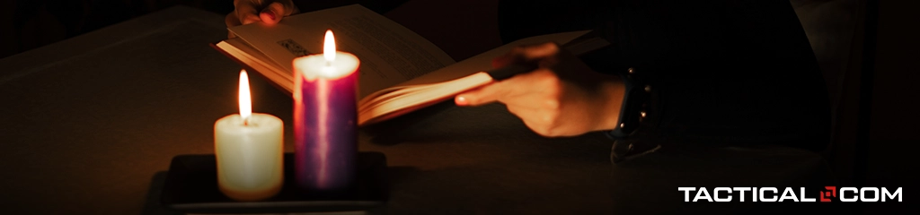 someone reading in the dark with two candles lit up
